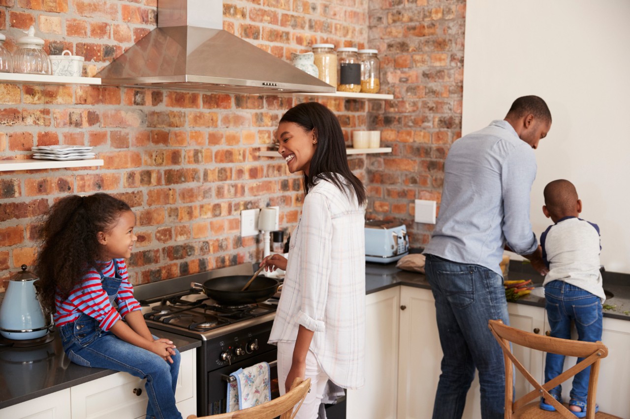 Children Helping Parents To Prepare Meal In Kitchen