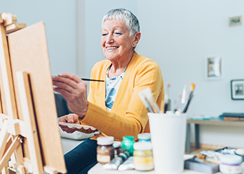 Person painting a canvas with paintbrushes