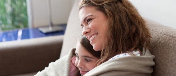 Mom smiling and sitting with her daughter wrapped in blankets