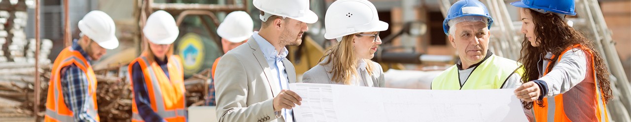Builders standing and reviewing a construction site plan