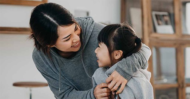 woman putting jacket on child