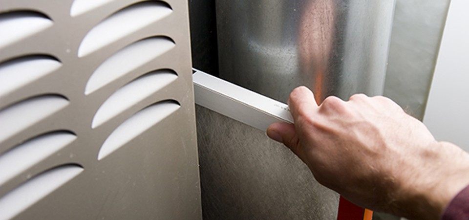 Hand placing new filter into furnace